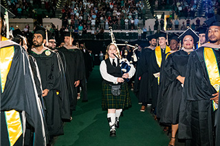 Woman plays bagpipes at commencement