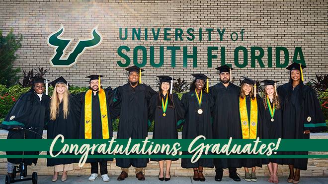 10 usf graduates in their robes and mortar boards standing in front of the usf logo on the wall outside SVC with "Congratulations Graduates!"