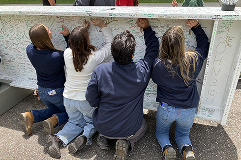 Four student interns sign construction beam for on-campus stadium.